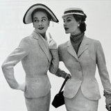 Two women in vintage suits and hats posing for a black and white photo.